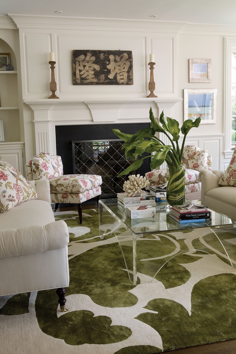 Living room with a white fireplace, floral armchairs, and a green botanical rug, Fairfield CT